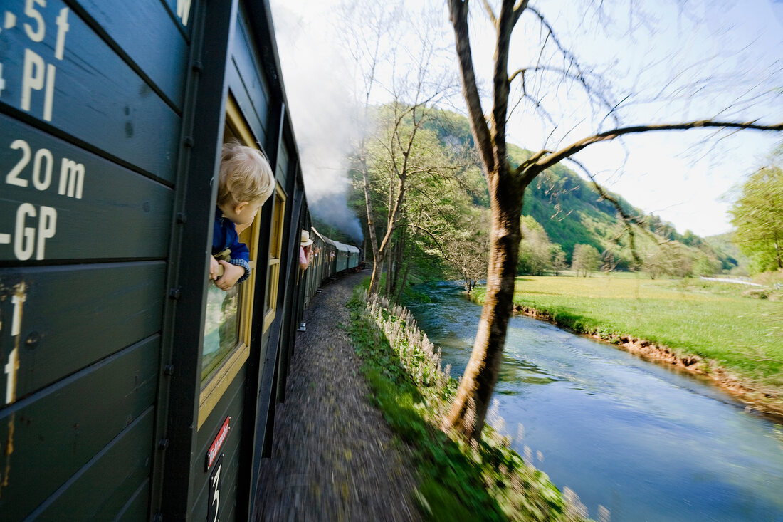 Boy peeping out of moving train in Franconian Switzerland, Bavaria, Germany