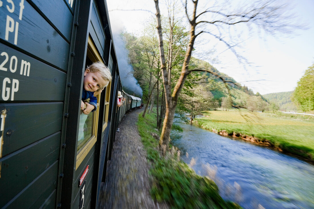 Boy peeping out of moving train in Franconian Switzerland, Bavaria, Germany