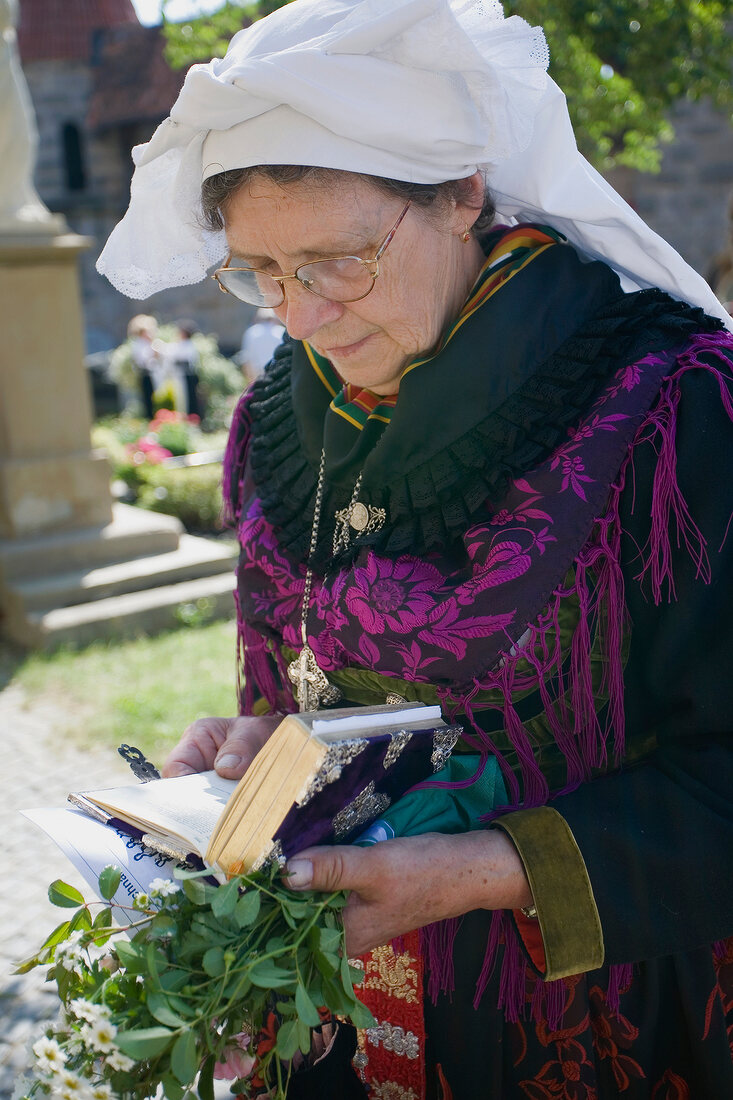 Senior woman wearing cornette praying in Franconian Switzerland, Bavaria, Germany
