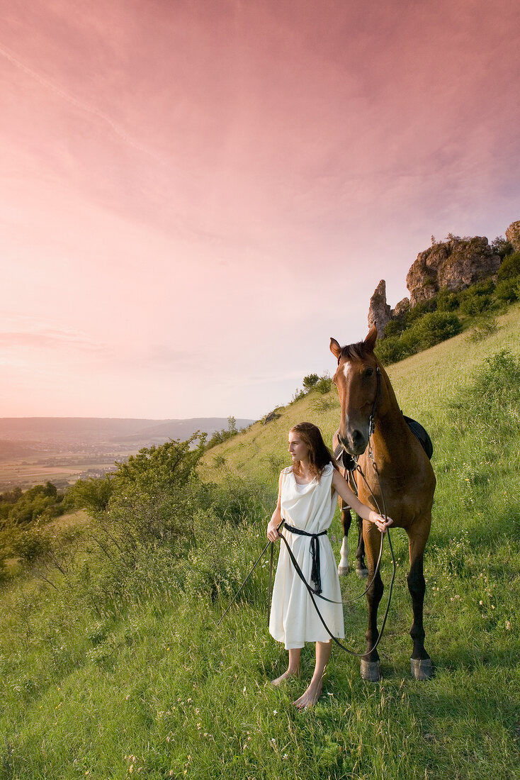 Woman with horse standing on mountain slope in Franconian Switzerland, Bavaria, Germany