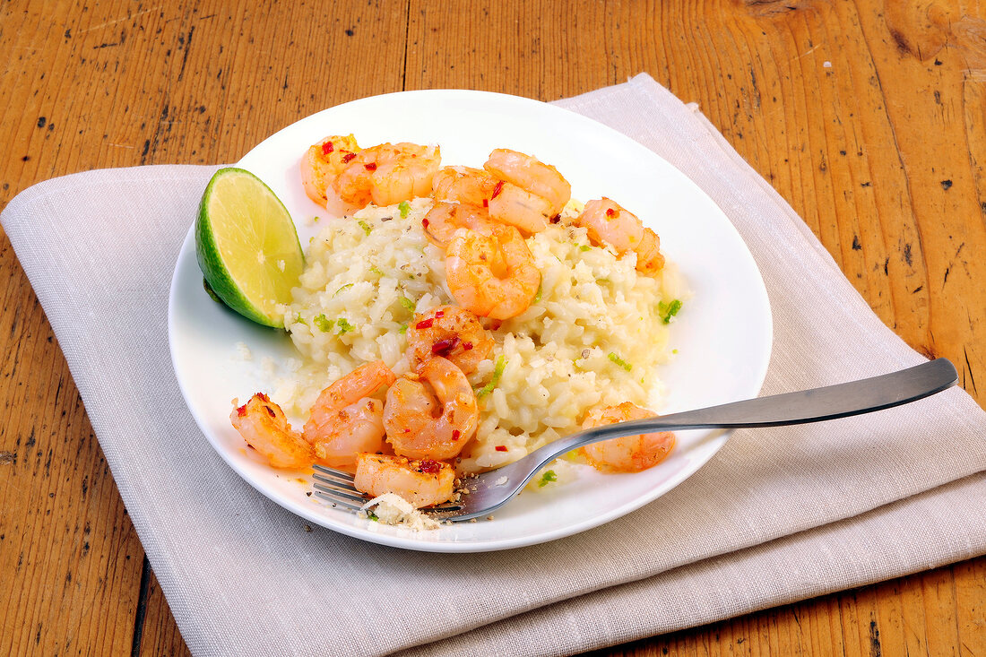 Lime risotto with chilli prawns and halved lemon on plate