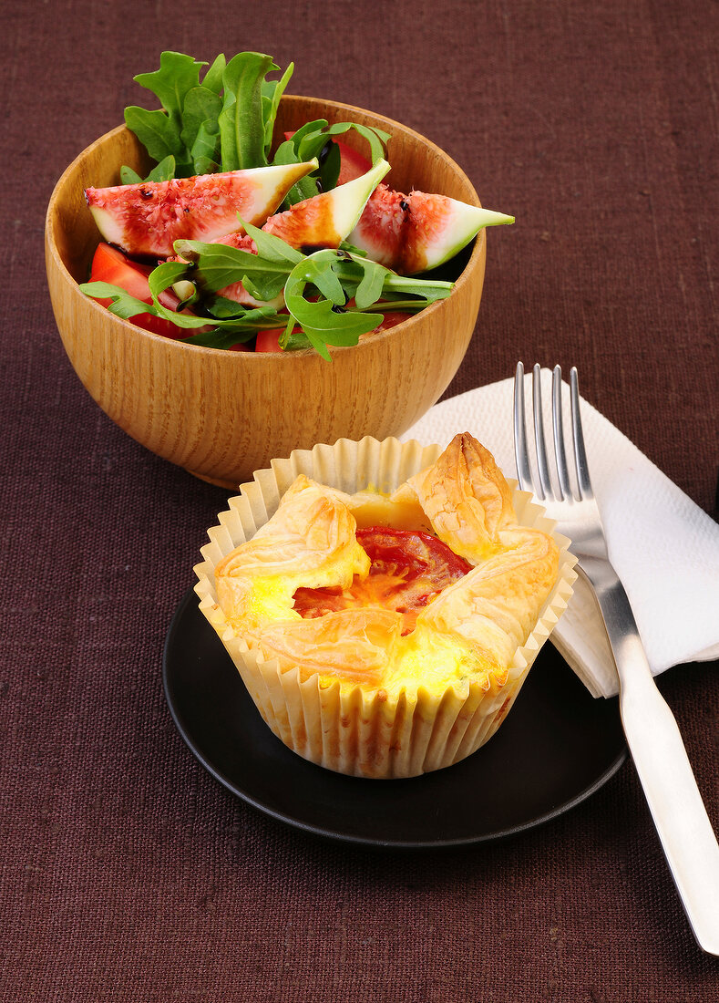 Puff muffin with tomato on plate and fig salad in bowl
