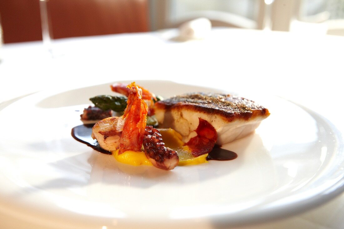 Close-up of sea bass, octopus and chorizo terrine with mandarin peel puree on plate