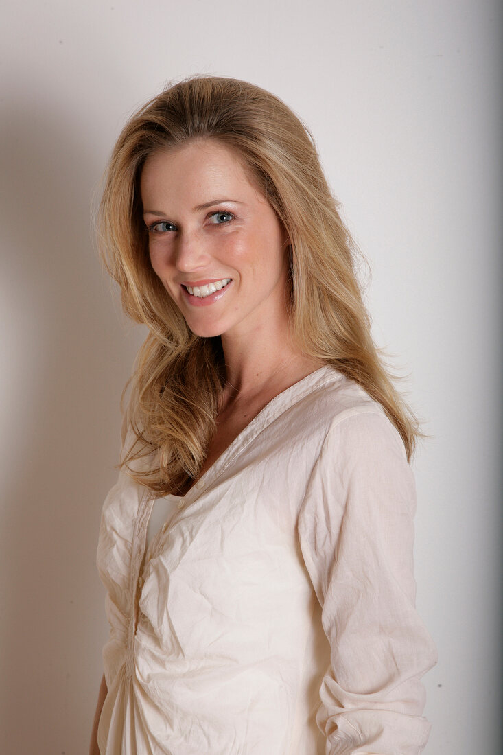 Portrait of pretty blonde woman wearing beige blouse, smiling