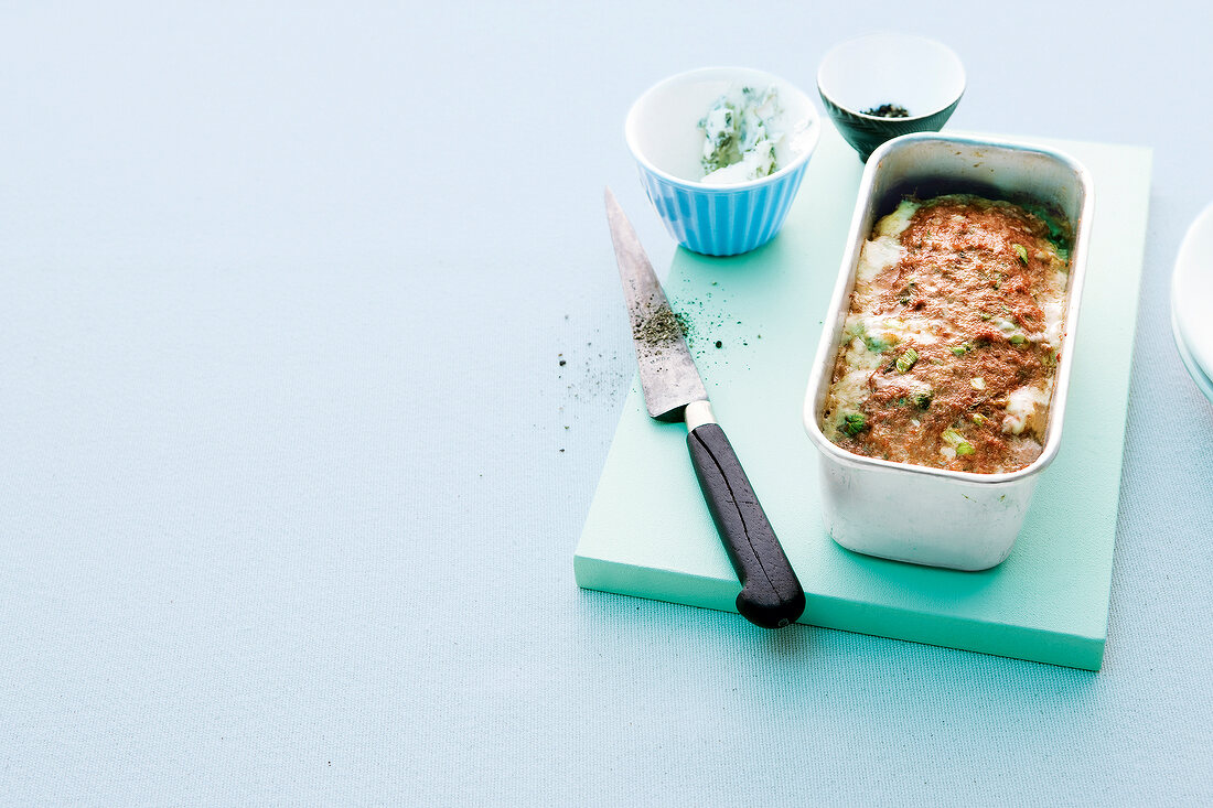 Gorgonzola meatloaf in baking tin with knife on chopping board