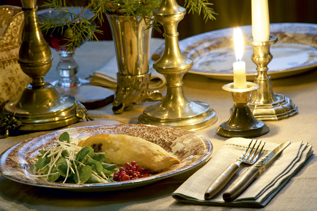 Corn salad, pheasant strudel and burning candle on table