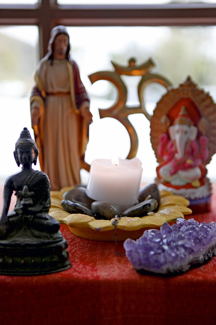 Close-up of lit candle with various god figures