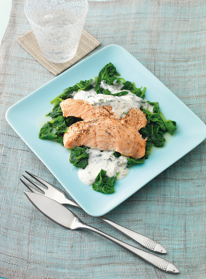 Steamed and sliced salmon with spinach on square blue plate