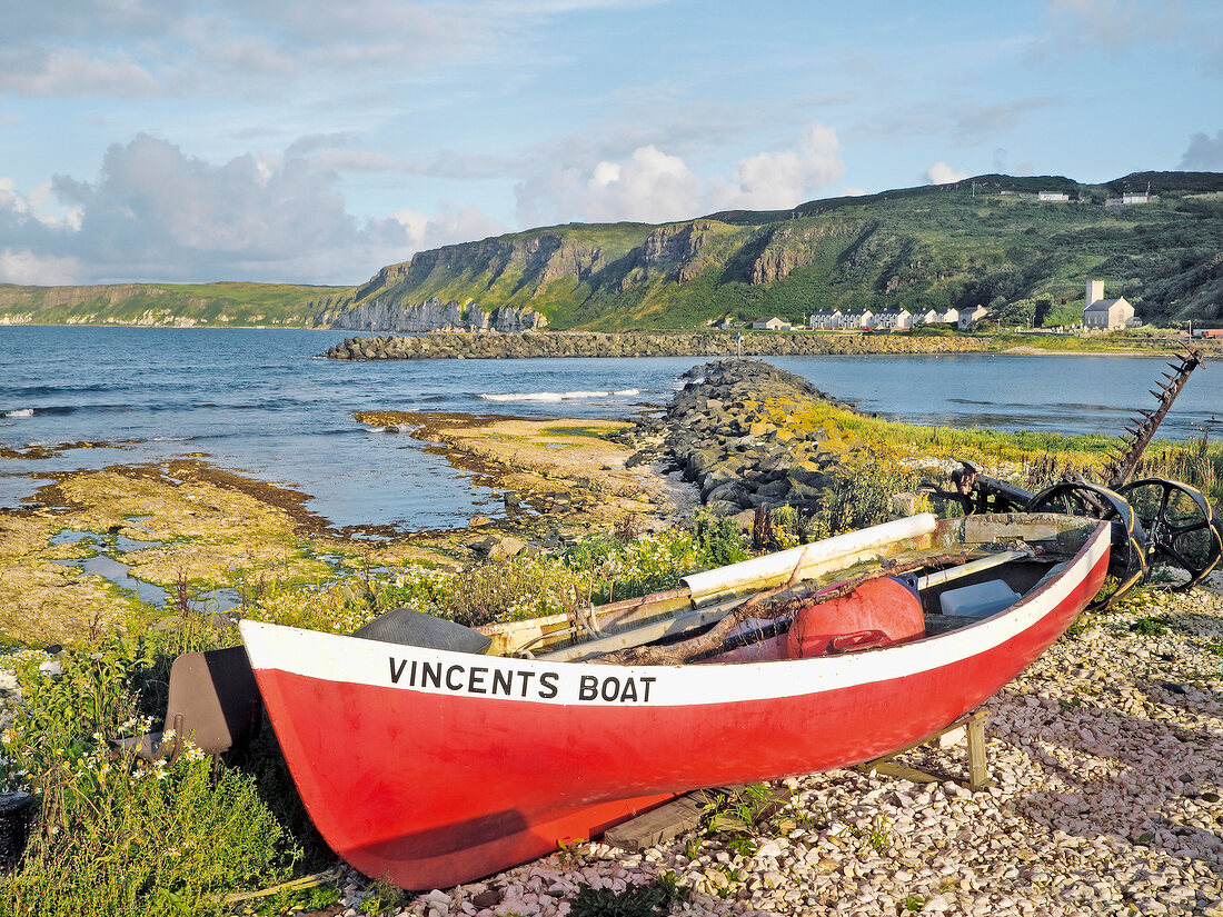Red boat on rocky coast of Rathlin Island in Ireland