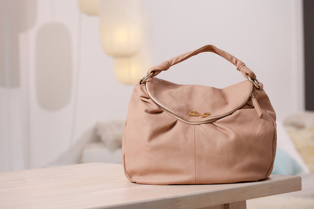 Pink handbag with zipper on wooden surface