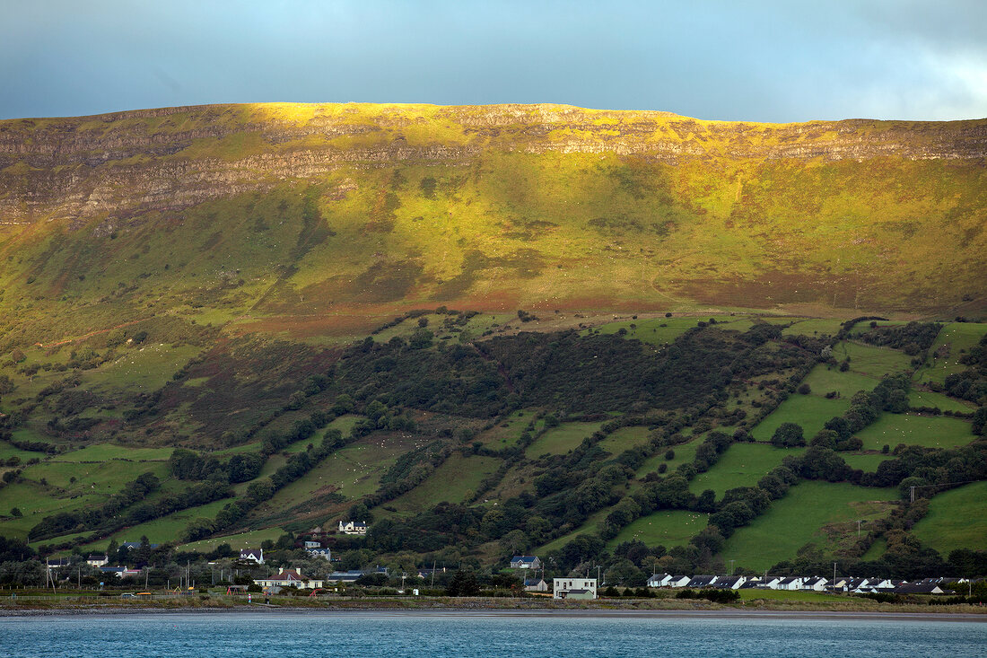 View of green pastures and village at Antrim coast, Ireland, UK