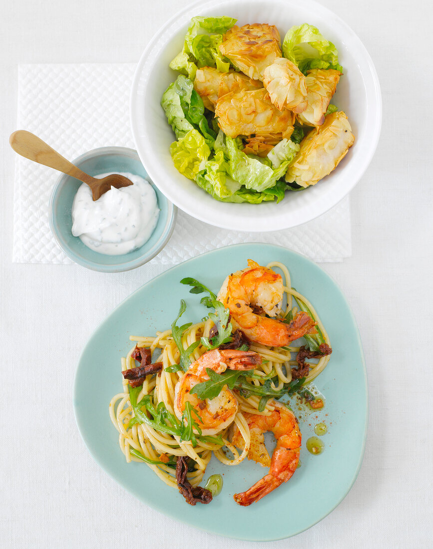 Fish nuggets in bowl and garlic shrimp with spaghetti on plate