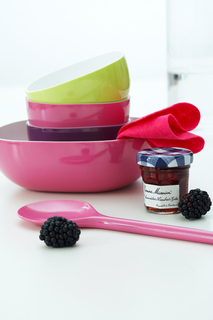 Colourful bowl set with spoon and blackberries on white surface
