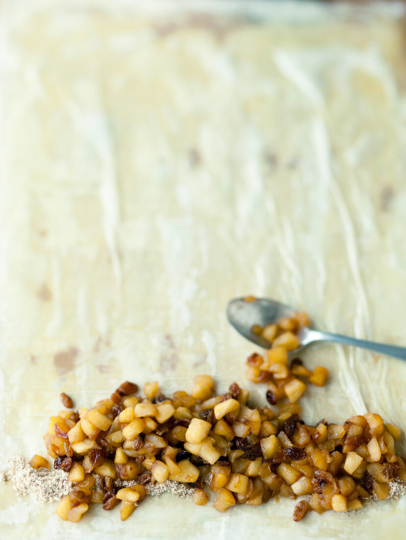 Chopped caramelized apples cubes being placed on filo pastry