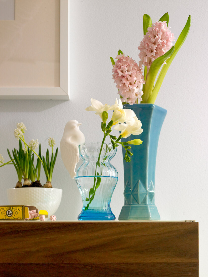 Spring flowers in vases on wooden surface