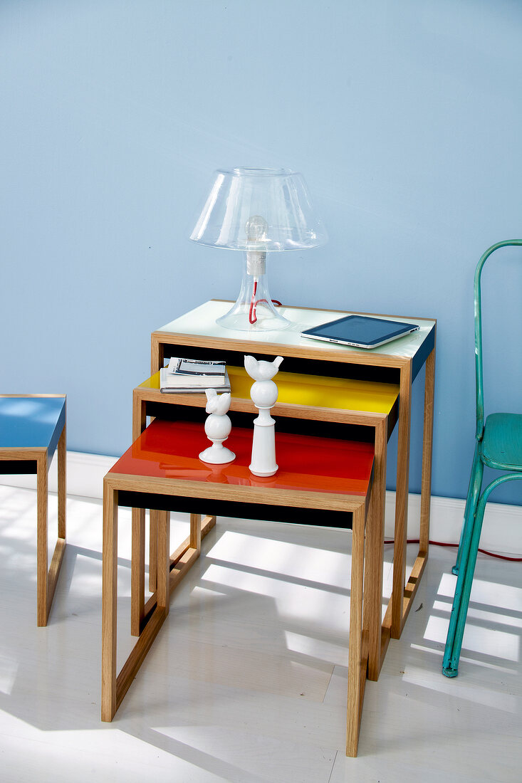 Three tables with different sized shelves against blue wall