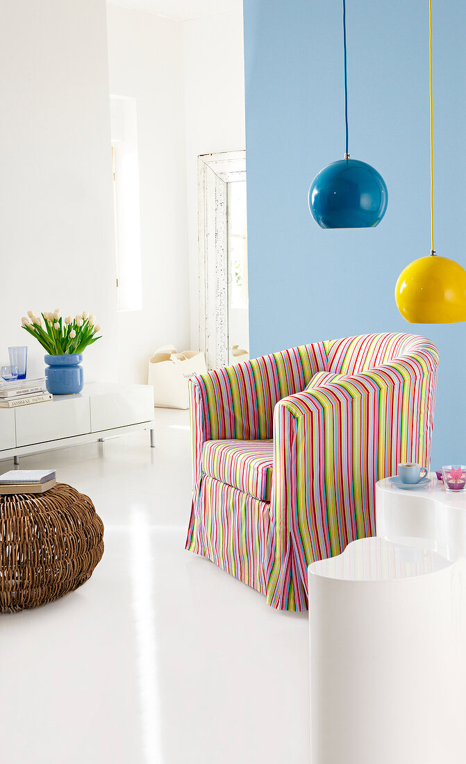 Armchair with colourful striped slipcover and blue and yellow globe lamp on top