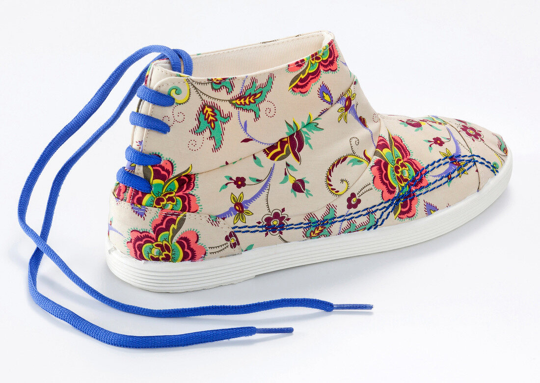 Colourful floral pattern sneaker with blue laces on white background