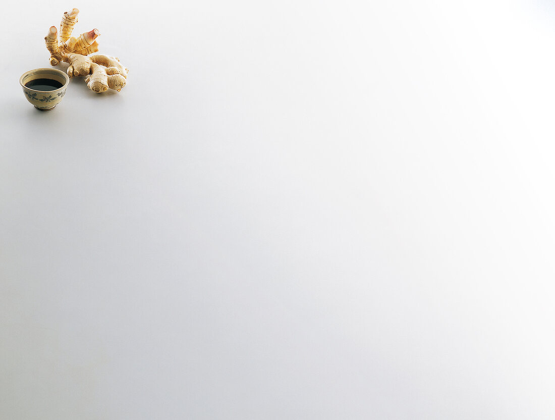 Bowl of soy sauce, ginger and galangal on white background, copy space