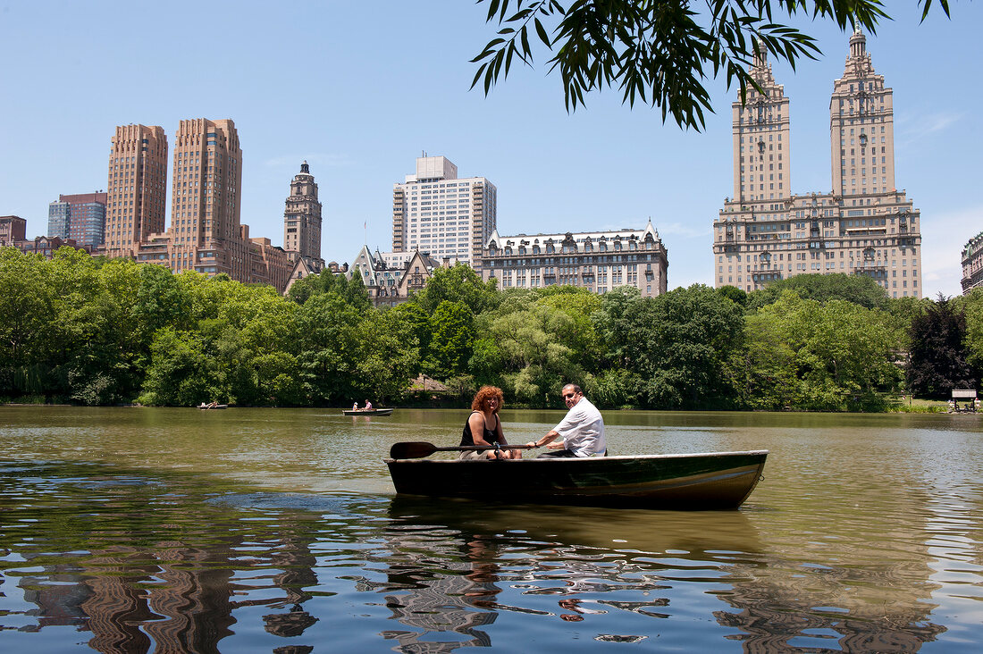 Couple on boat at Central park lake overlooking The Dakota, New York, USA