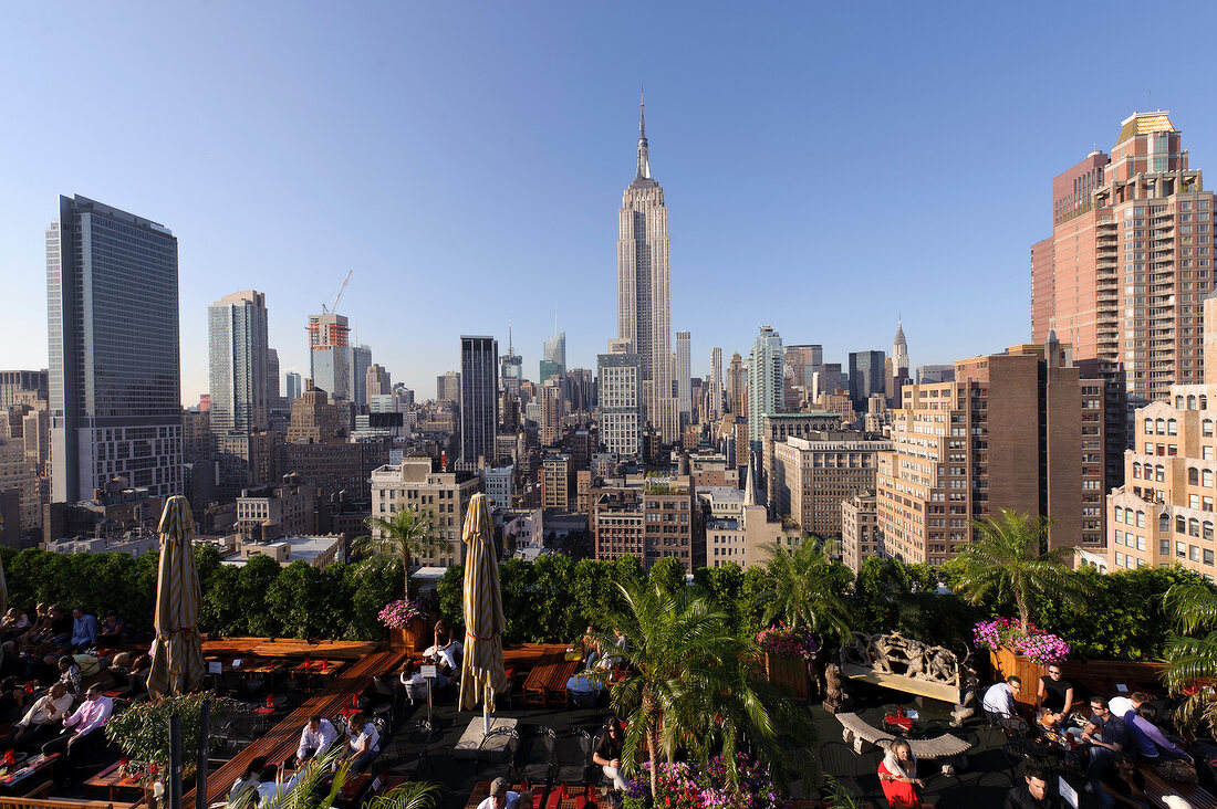 View of cityscape overlooking people sitting on rooftop bar at New York, USA