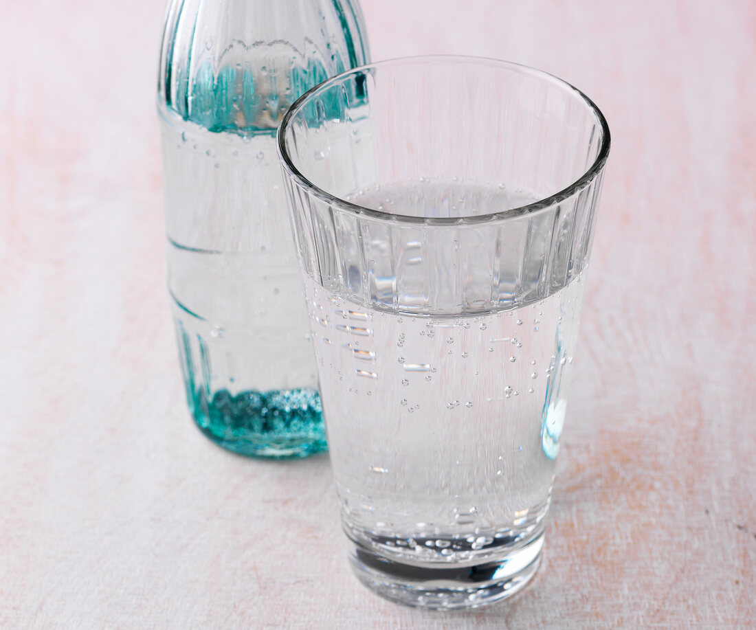 Close-up of glass and bottle filled with mineral water