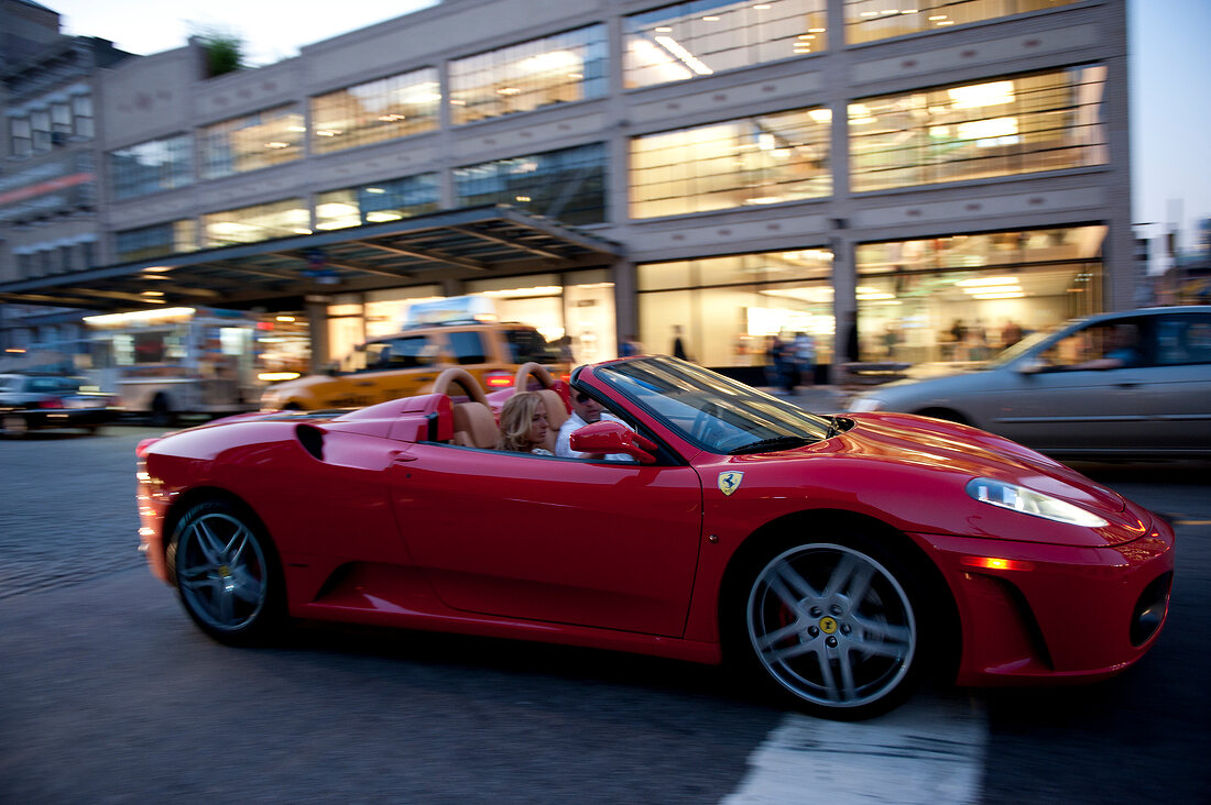 People driving red Ferrari in front of Apple store in New York, USA