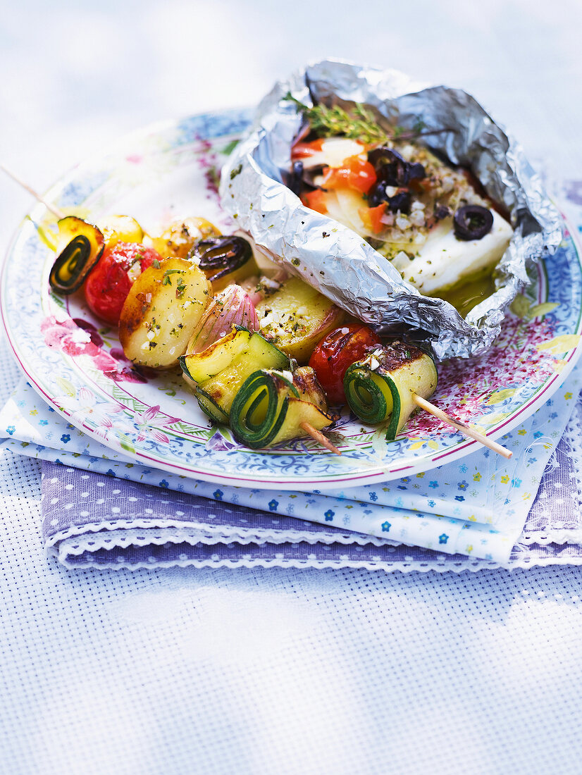Vegetable skewers with feta parcel on plate in summer kitchen
