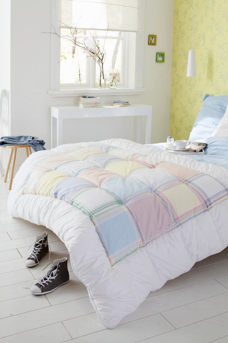 Bett mit Patchworkbettdecke im schlichten Schlafzimmer