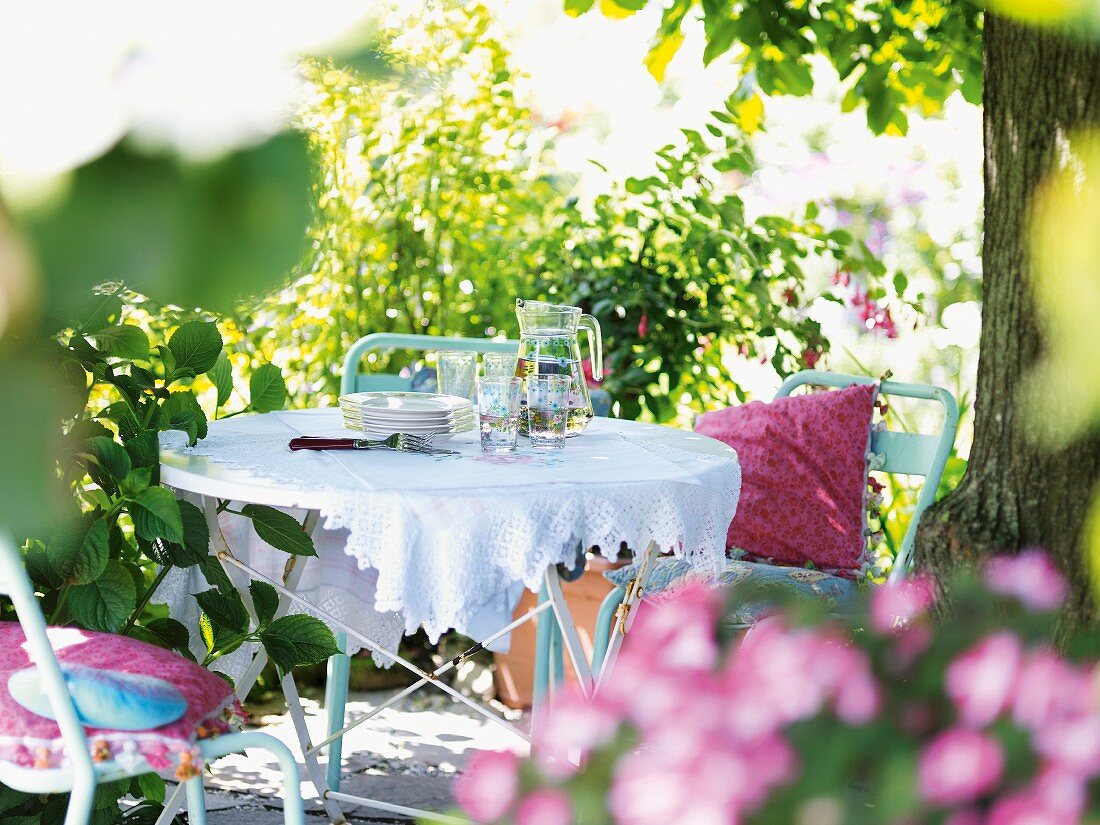 Crockery and glasses on a table in a summery garden