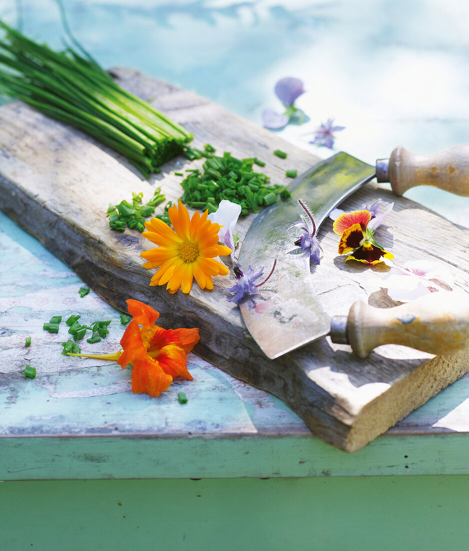 Chopped flowers and chives on wooden chopping board