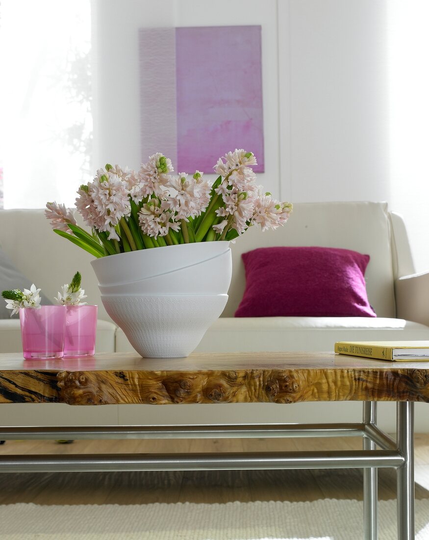 Vase of pink hyacinths on table against white couch