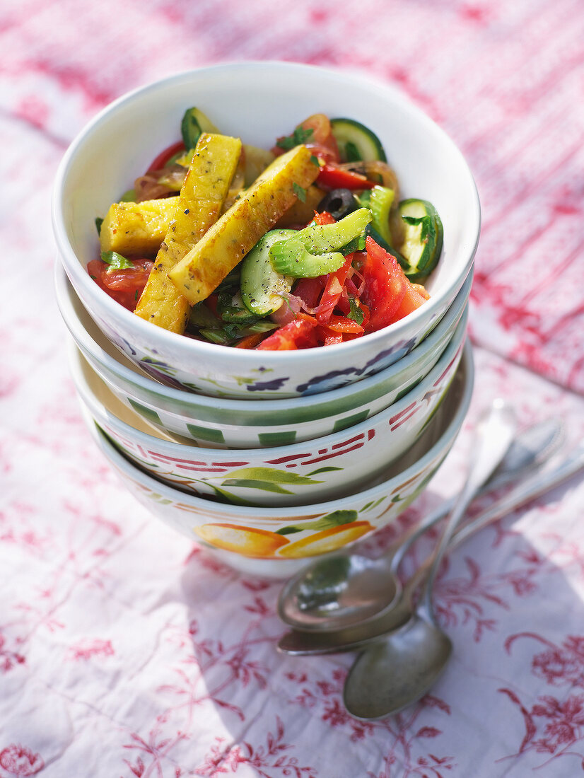 Vegetables with chickpeas sticks in stack of bowls in summer kitchen