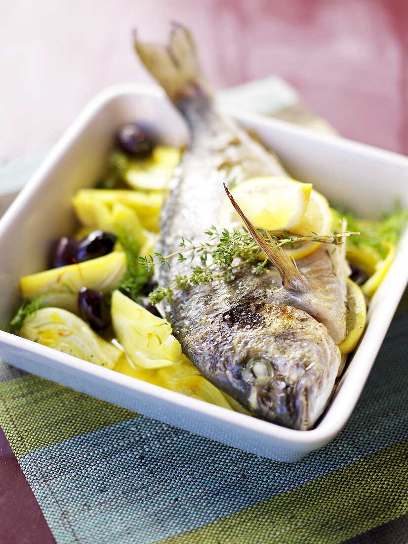 Bream on fennel with black olives on serving dish