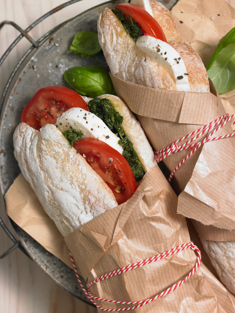 Close-up of caprese sandwiches wrapped in brown paper and tied with strings