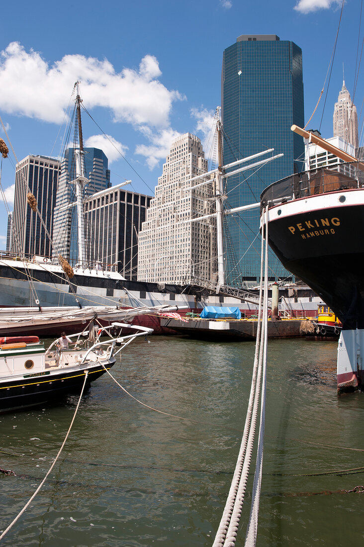 Ships moored at harbour with skyscrapers and bridge in background at New York, USA