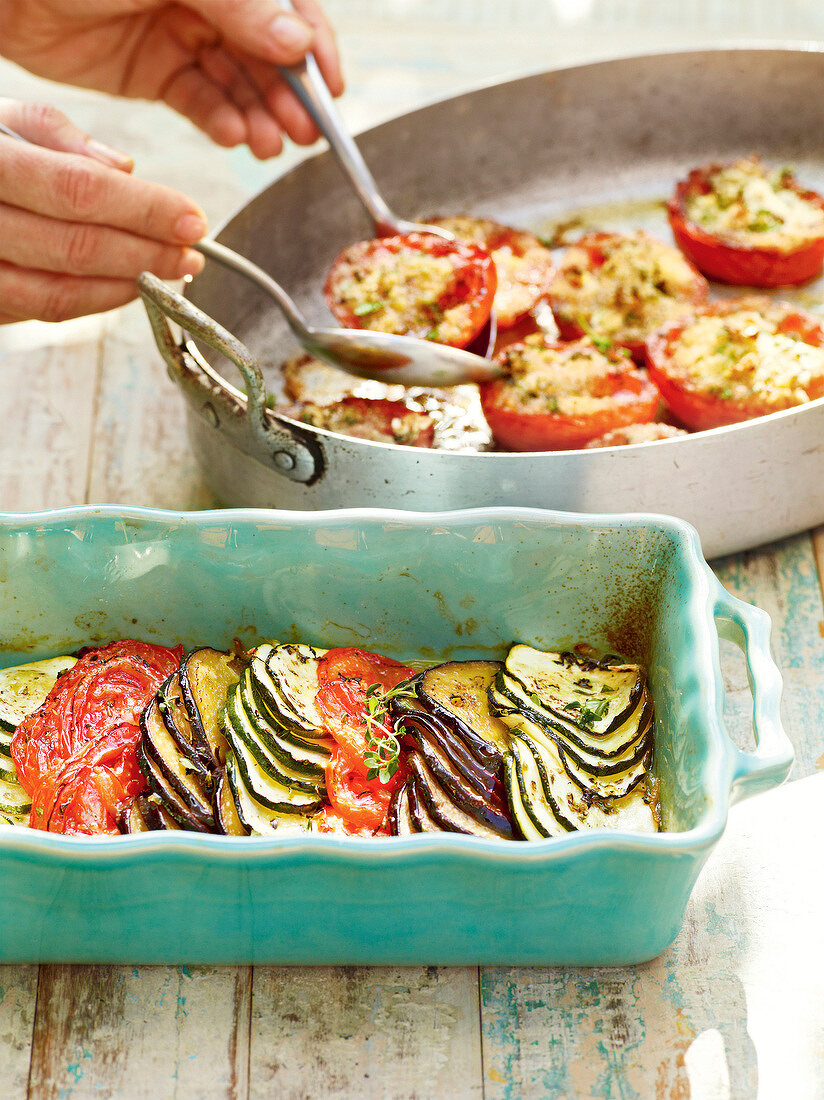 Close-up of hand serving provencal vegetable gratin in baking tray
