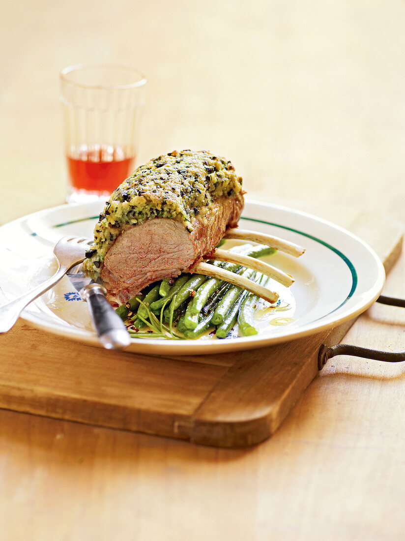 Rack of lamb with coating of herbs and olive mixture on plate, France