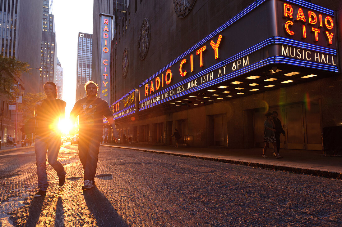 People passing the Radio City Music Hall at sunset, New York, USA