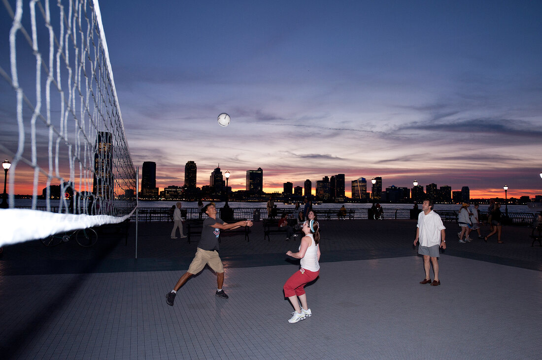 People playing volleyball at the bank of Hudson River at dusk in New York, USA