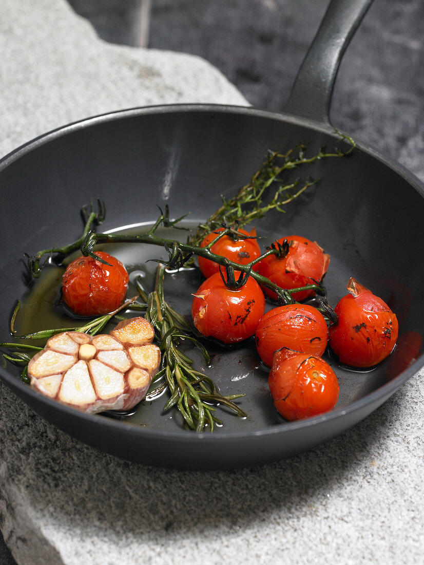 Tomatoes with garlic and rosemary in frying pan