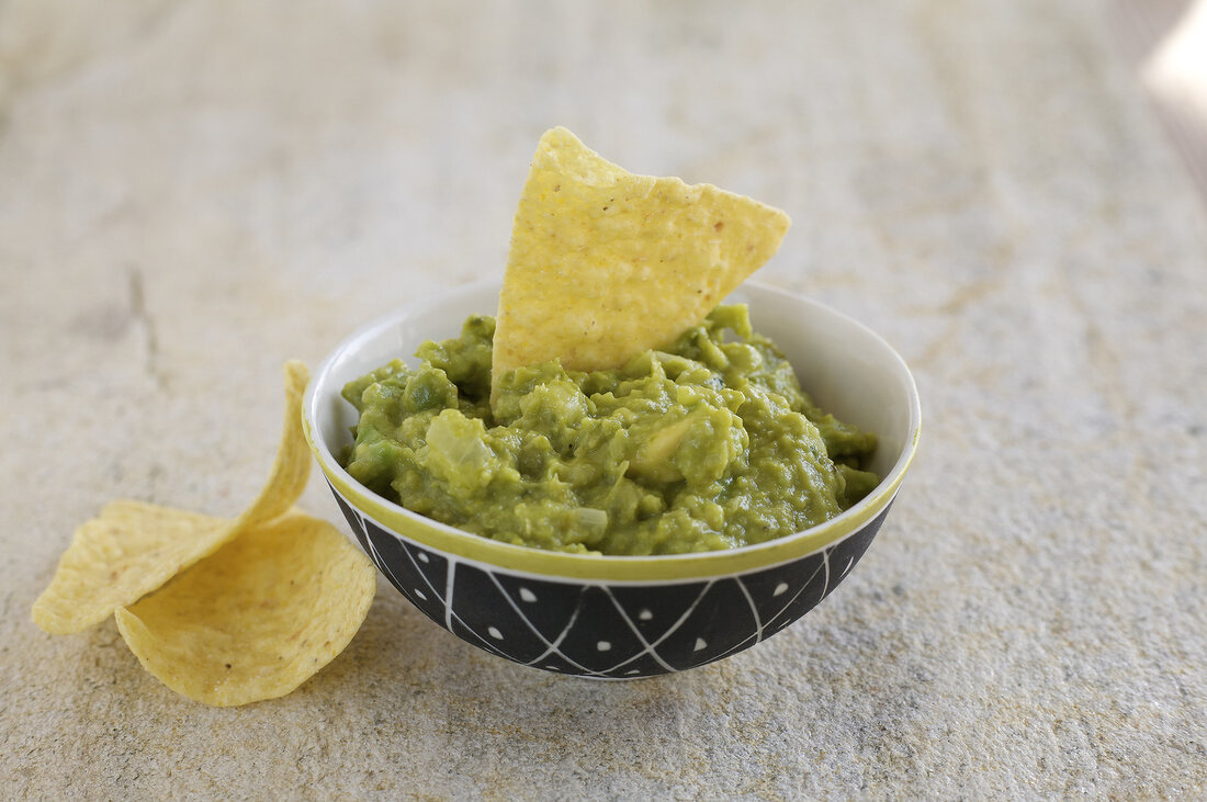 Chip in pea and avocado dip in bowl