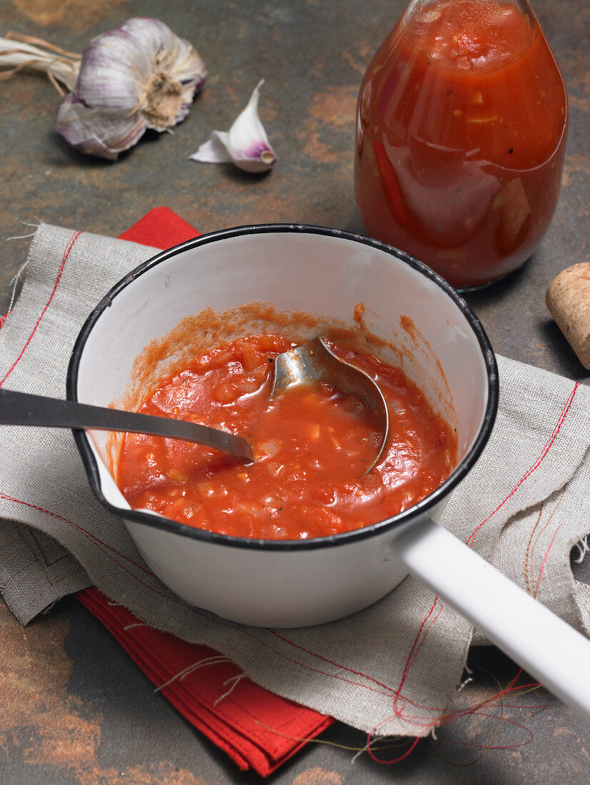 Pot with tomato sauce and spoon