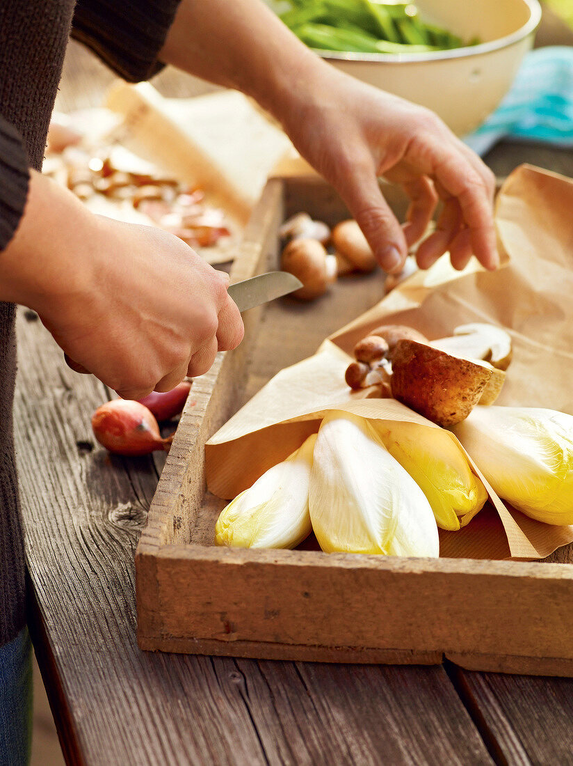 Close-up of man cleaning and cutting mushrooms with knife, France