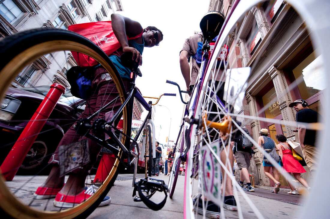 Low angle view of two people standing with bicycles on Broadway in Soho, New York, USA