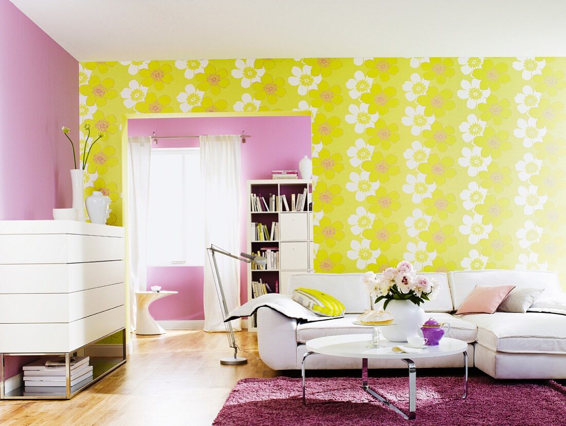 Wohnzimmer mit weissen Möbeln, lila Wand und großgemusterter Blütentapete in Gelb