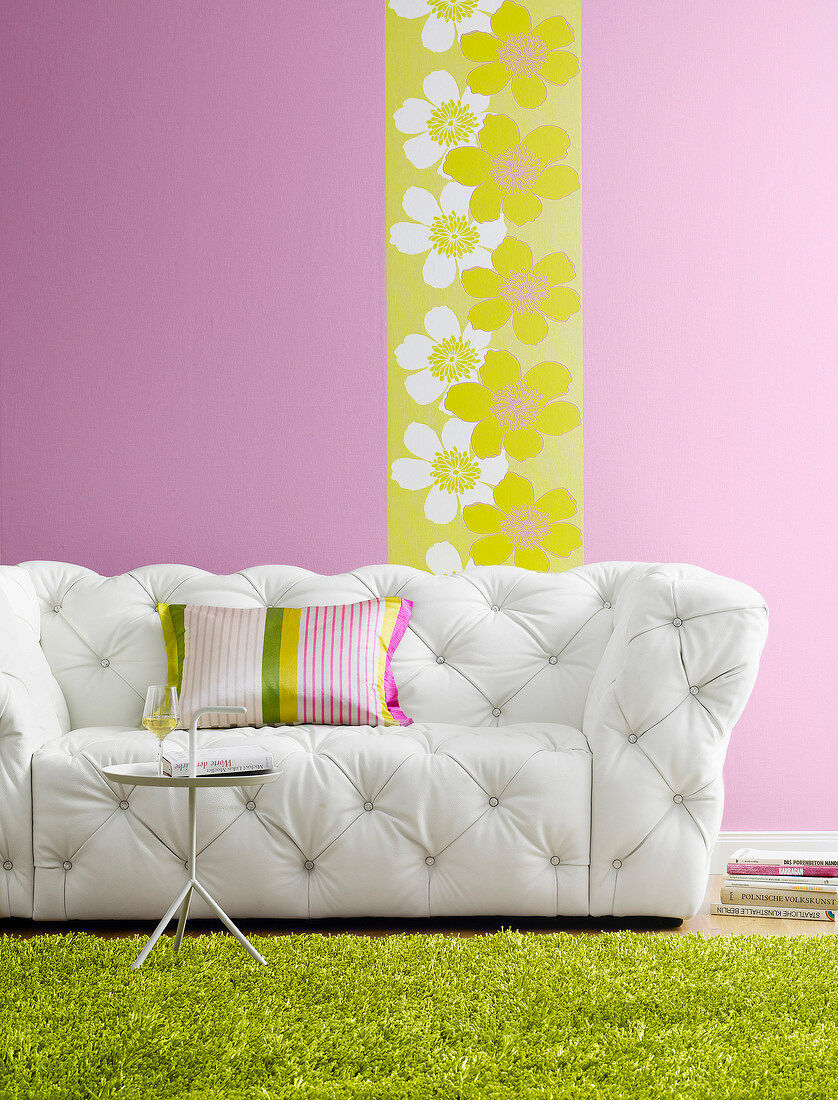White sofa in front of floral pattern wall