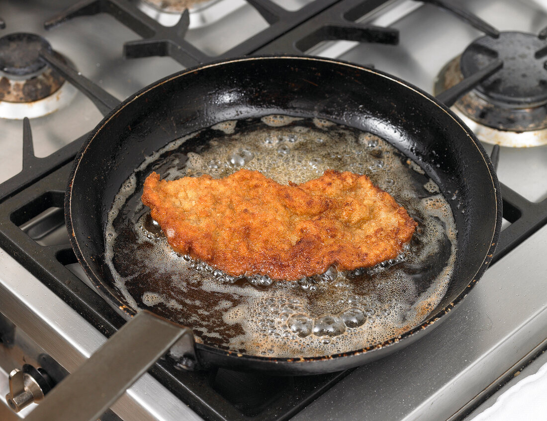 Frying meat in ghee for preparation of schnitzel, step 3