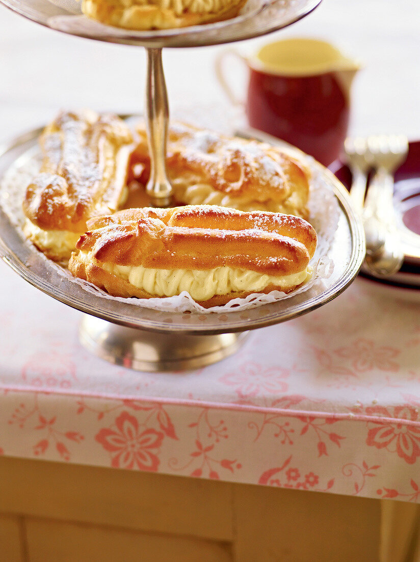 Eclairs with icing sugar on tier cake stand, France
