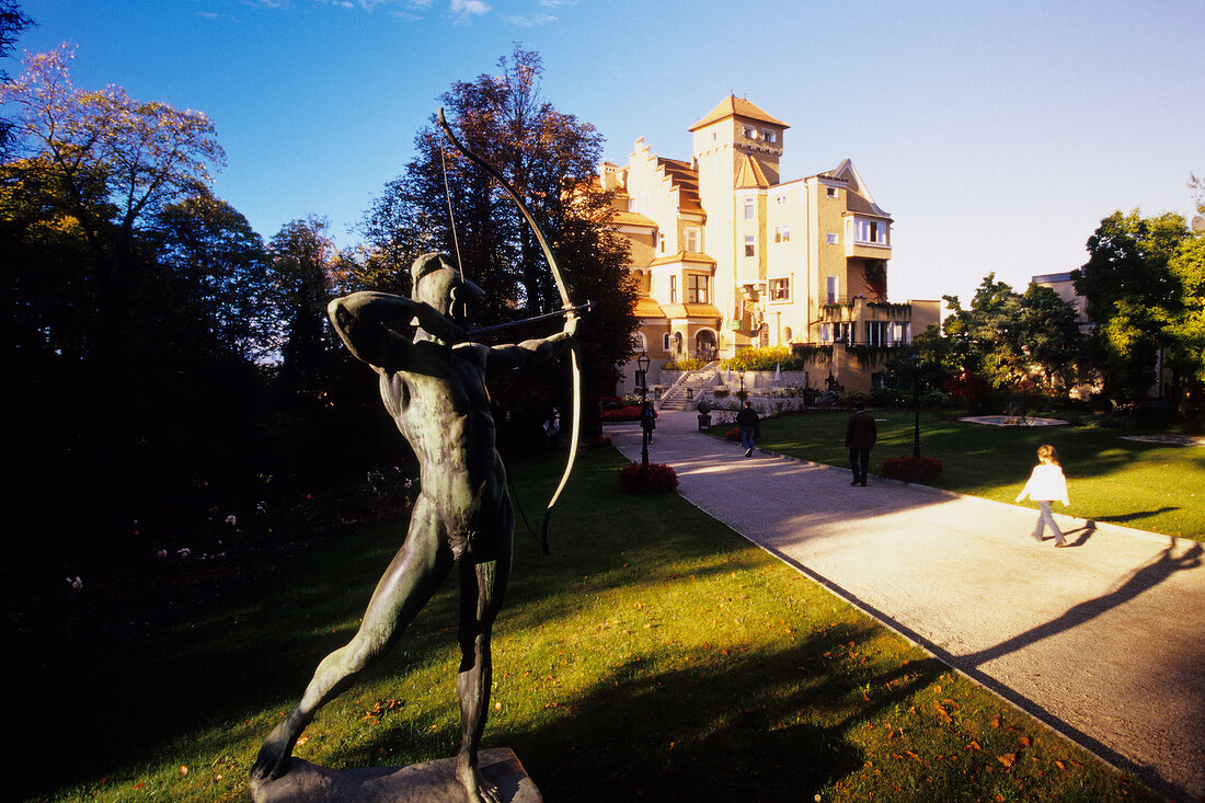 Statue holding bow and arrow near stone castle, Salzburg, Austria